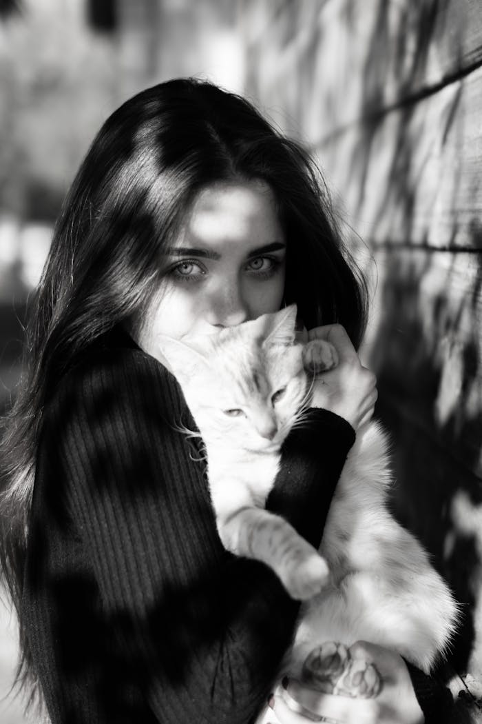 Captivating black and white portrait of a woman holding her cat outdoors.